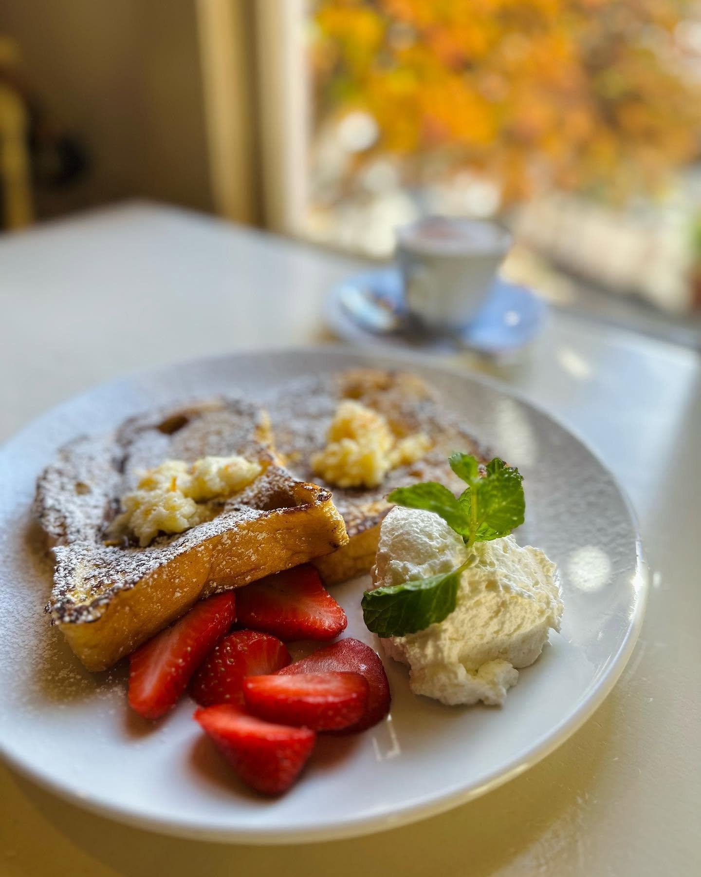 Cinnamon brioche French toast with fresh strawberries and cream by the window
